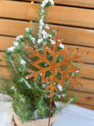 Schneekristall aus gerostetem Metall als Stecker im winterlichen Kübel
