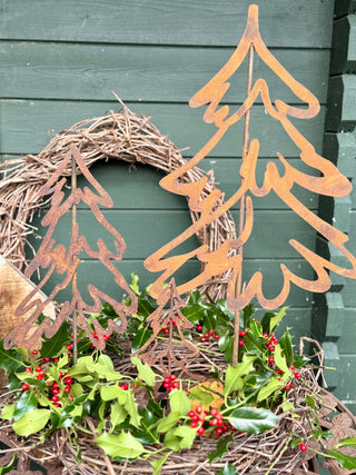 Tannenbäume aus Rost mit Rebenkranz und Ilex vor einer Holzwand