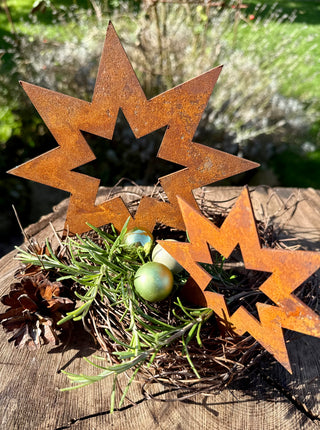 Stern offen hochkant aus gerostetem Metall, zwei Größen mit Tannengrün und Christbaumkugeln, Nahaufnahme